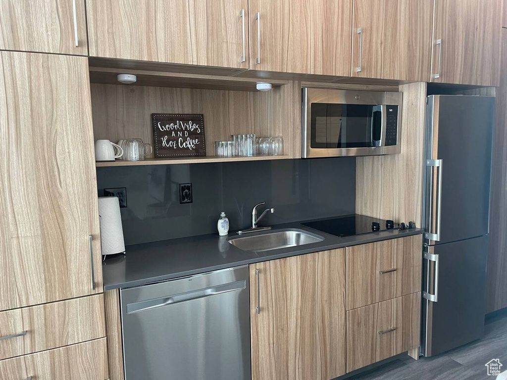 Kitchen featuring dark hardwood / wood-style flooring, sink, stainless steel appliances, and backsplash