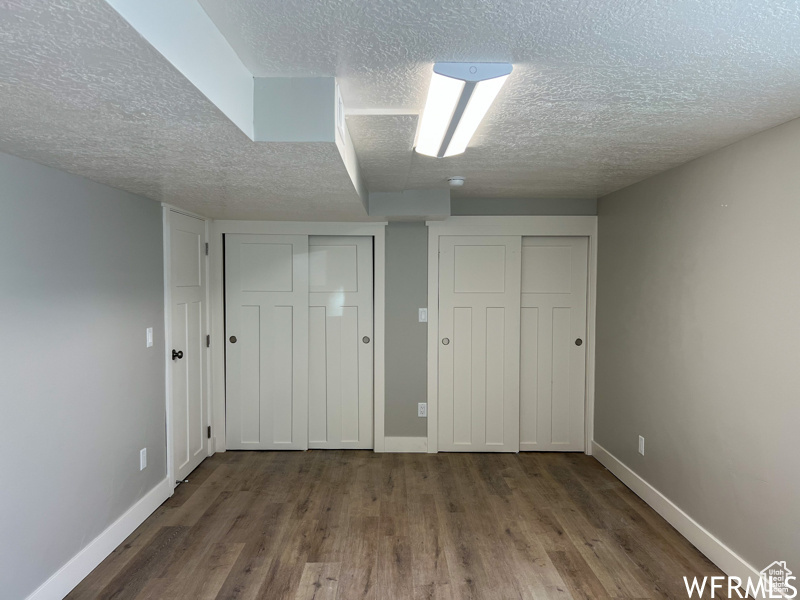 Unfurnished bedroom featuring dark wood-type flooring, multiple closets, and a textured ceiling