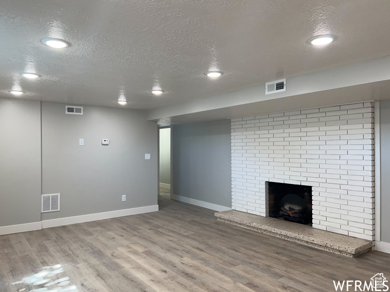 Interior space featuring a brick fireplace, brick wall, dark hardwood / wood-style flooring, and a textured ceiling