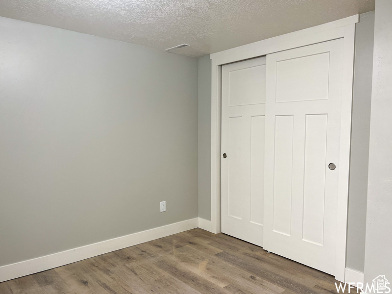 Unfurnished bedroom featuring dark hardwood / wood-style floors, a closet, and a textured ceiling