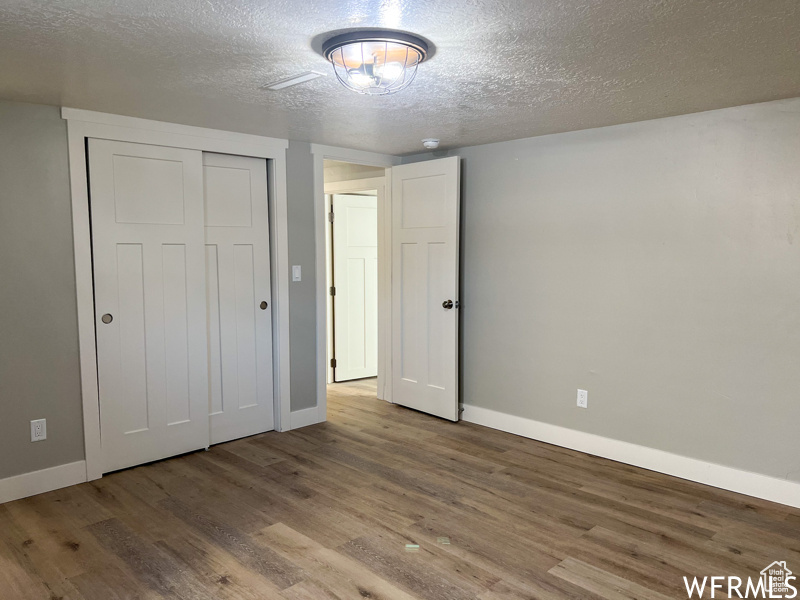 Unfurnished bedroom featuring dark wood-type flooring, a closet, and a textured ceiling