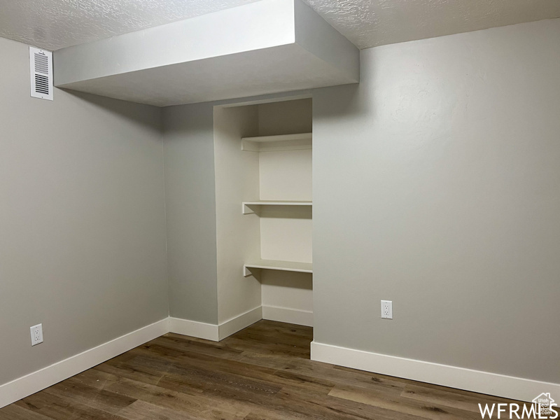 Spare room featuring a textured ceiling and dark wood-type flooring