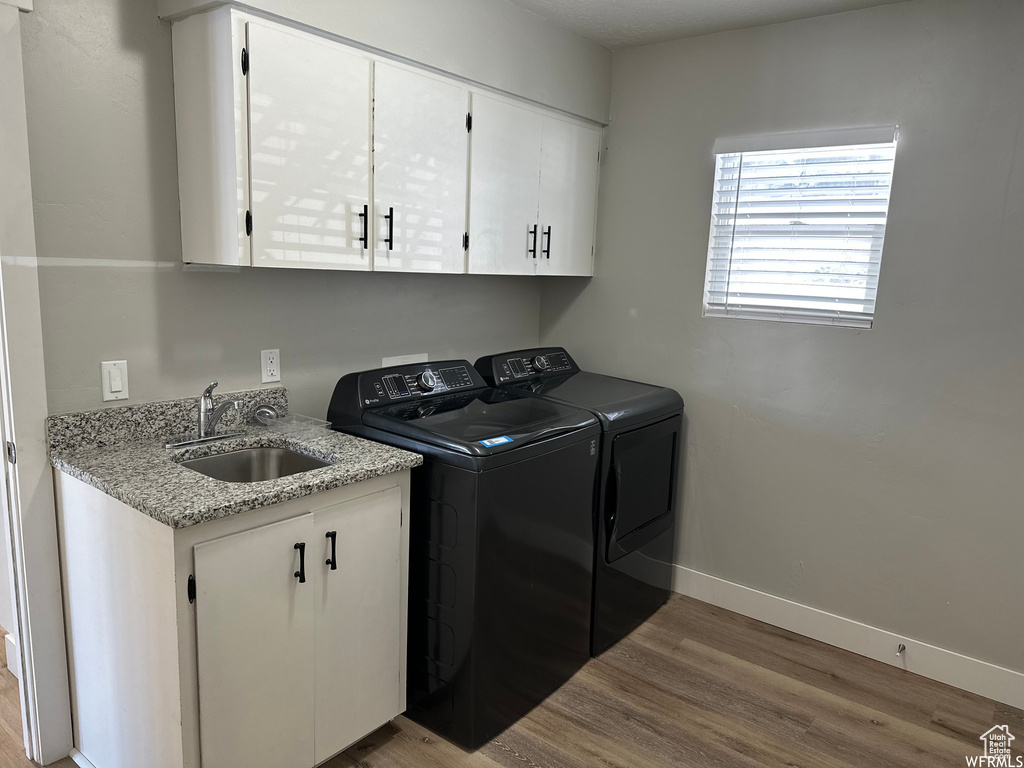 Washroom with sink, separate washer and dryer, cabinets, and hardwood / wood-style flooring