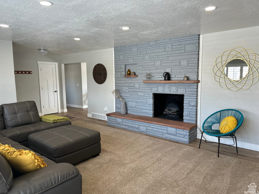 Carpeted living room featuring a textured ceiling and a fireplace