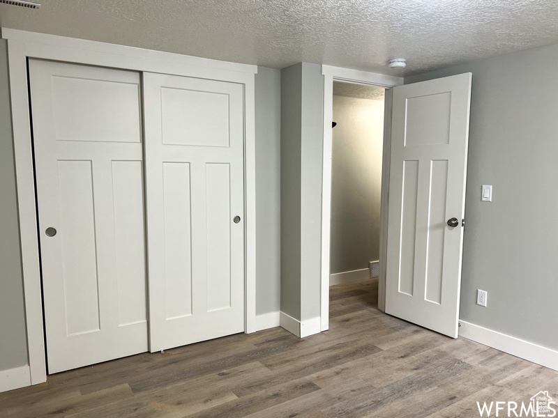 Unfurnished bedroom with a closet, a textured ceiling, and dark hardwood / wood-style floors