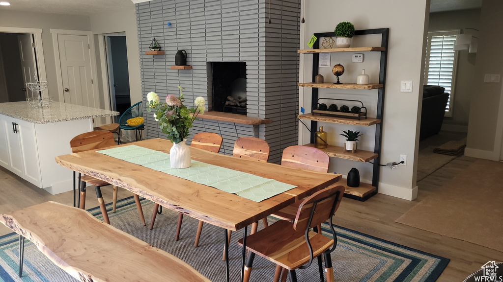 Dining space with light hardwood / wood-style floors and a fireplace