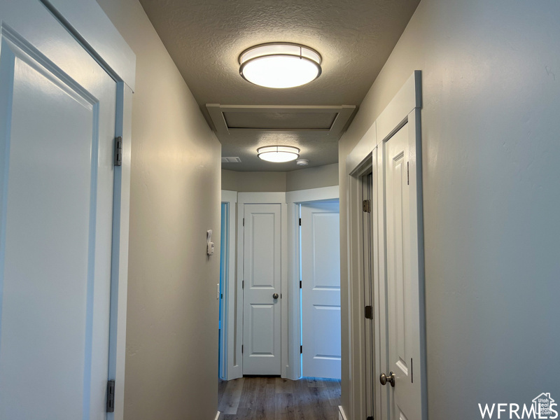 Hallway featuring a textured ceiling and dark wood-type flooring