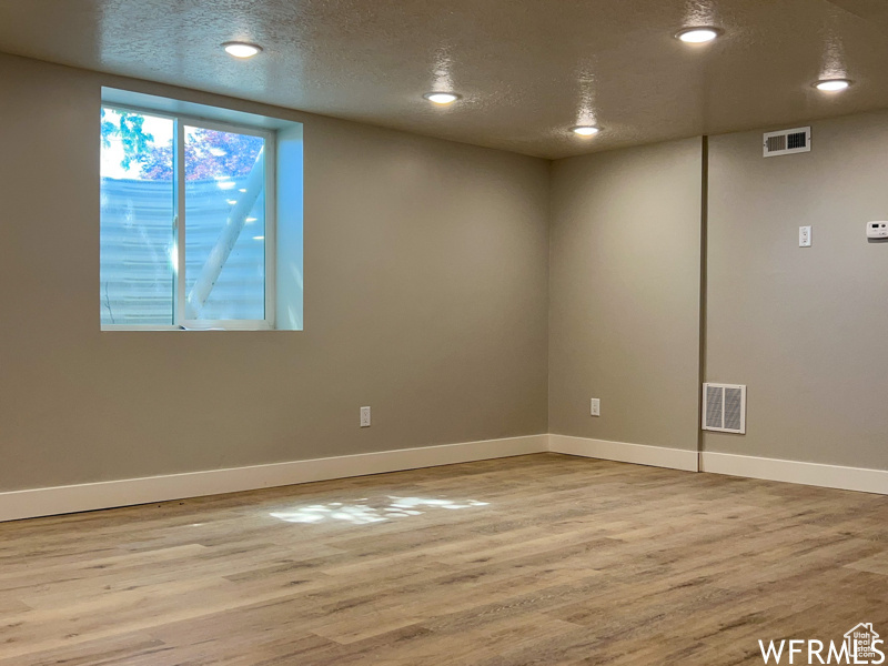 Unfurnished room with light hardwood / wood-style floors and a textured ceiling