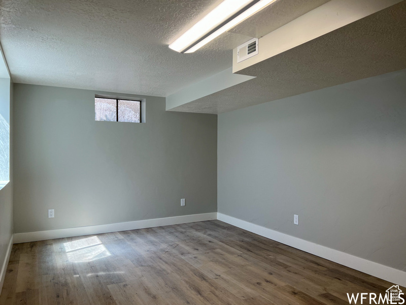 Basement with a textured ceiling and dark hardwood / wood-style floors