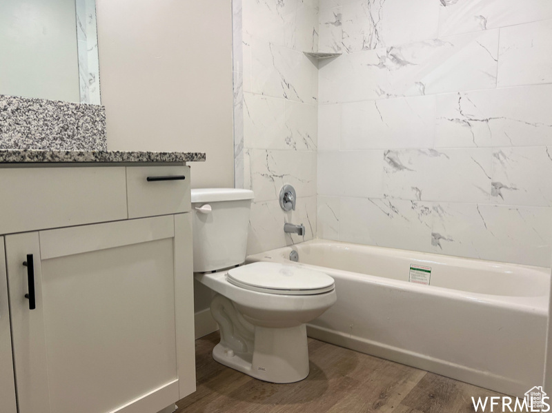 Full bathroom featuring vanity, tiled shower / bath combo, toilet, and hardwood / wood-style floors