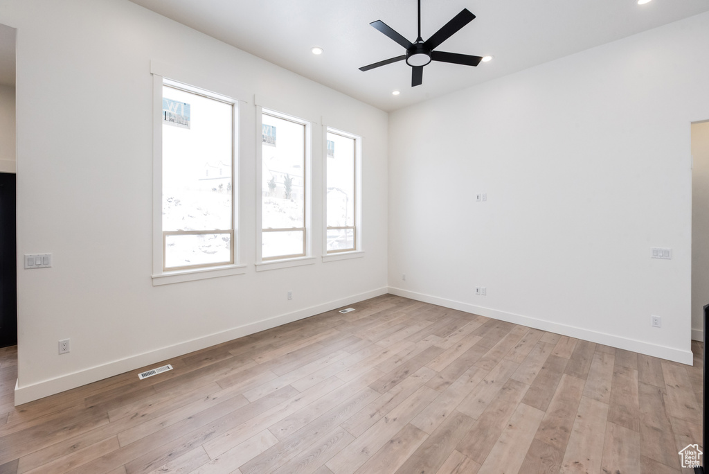 Empty room featuring light wood-type flooring, a wealth of natural light, and ceiling fan
