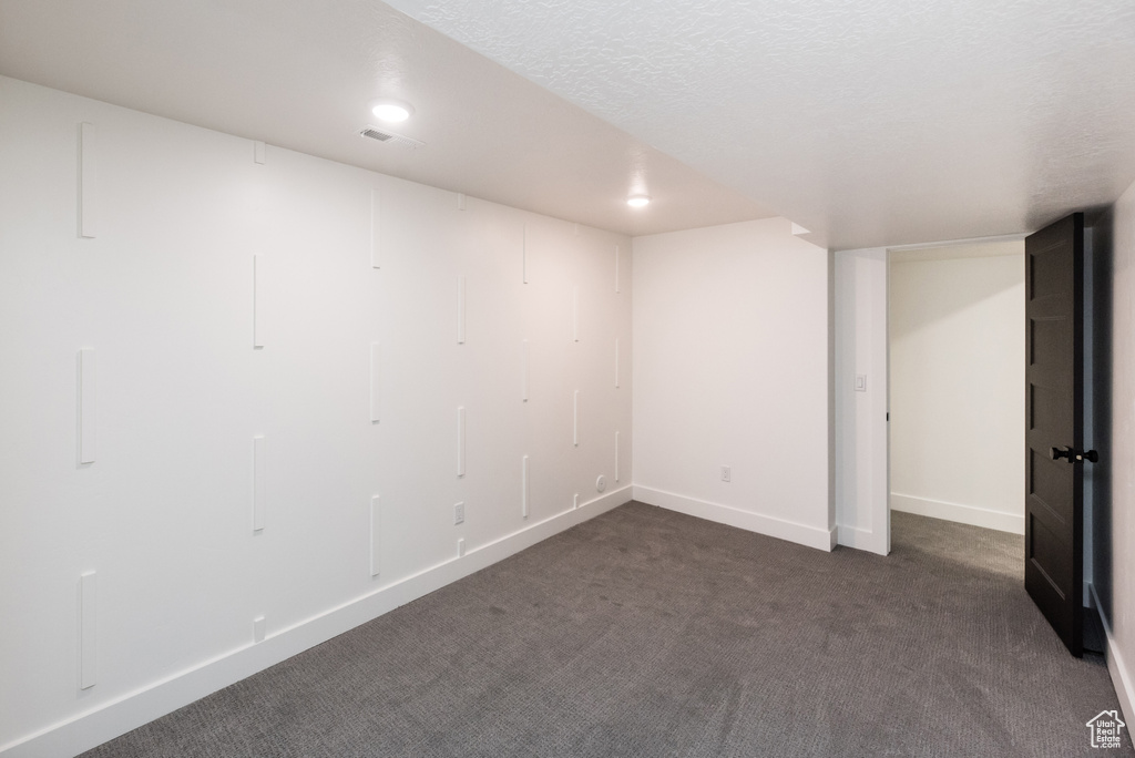 Unfurnished room with dark carpet and a textured ceiling