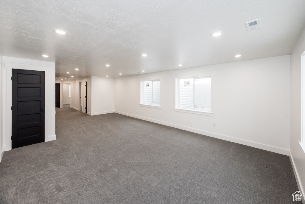 Empty room with dark carpet and a textured ceiling