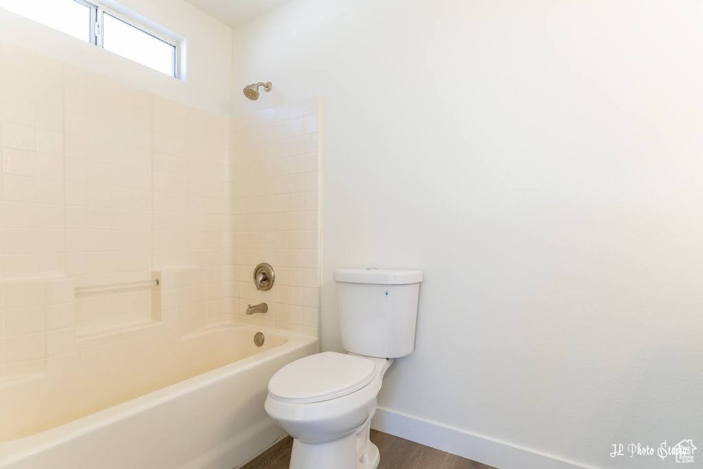 Bathroom with shower / bath combination, toilet, and hardwood / wood-style floors