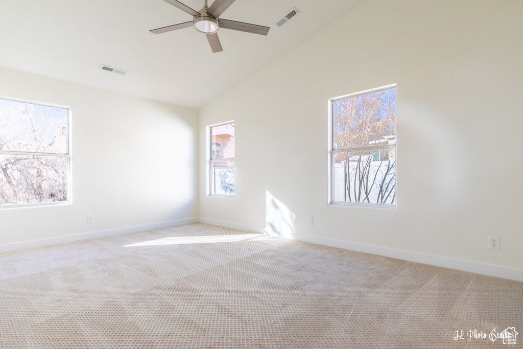 Carpeted spare room with lofted ceiling and ceiling fan