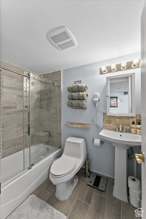 Full bathroom with tile floors, toilet, backsplash, sink, and enclosed tub / shower combo