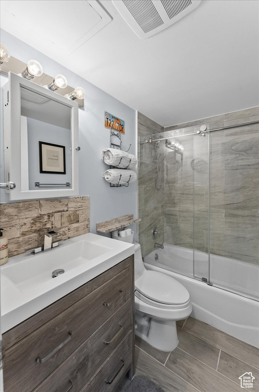 Full bathroom featuring tile floors, vanity, toilet, and enclosed tub / shower combo