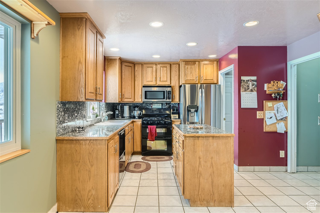 Kitchen featuring light tile flooring, stainless steel appliances, a kitchen island, sink, and tasteful backsplash
