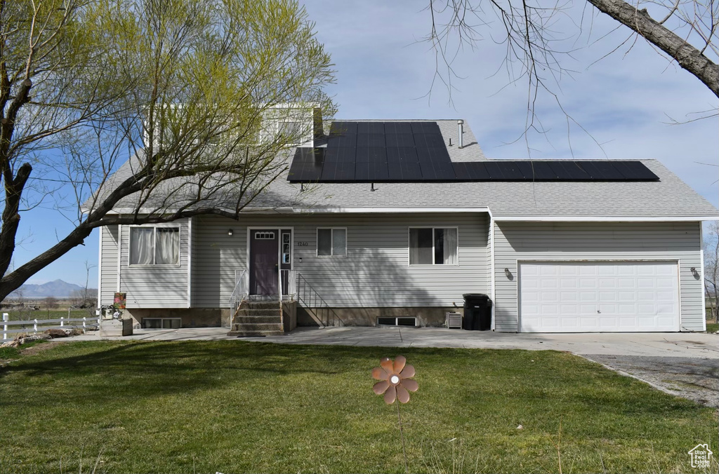 View of front of property featuring a front yard, a garage, and solar panels