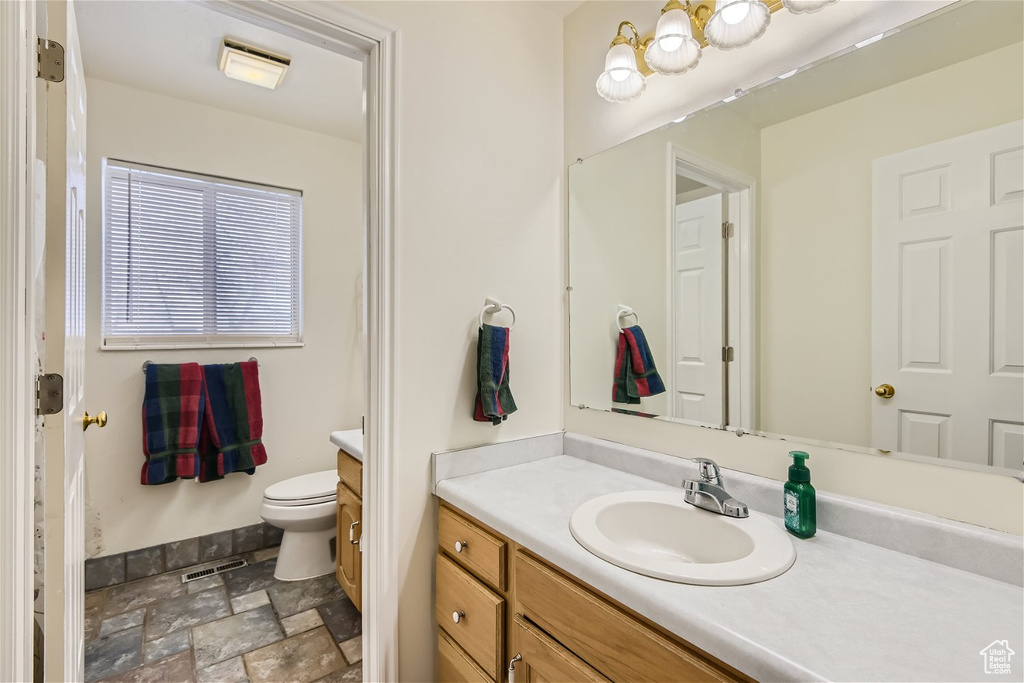 Bathroom with tile floors, vanity, toilet, and a notable chandelier