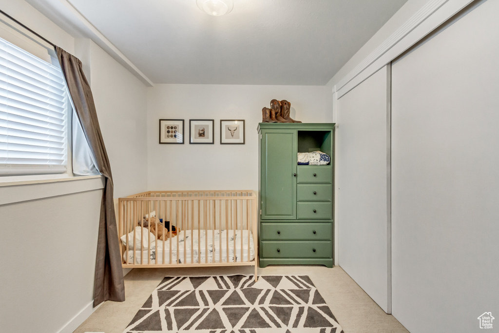 Bedroom with a crib, a closet, and light colored carpet