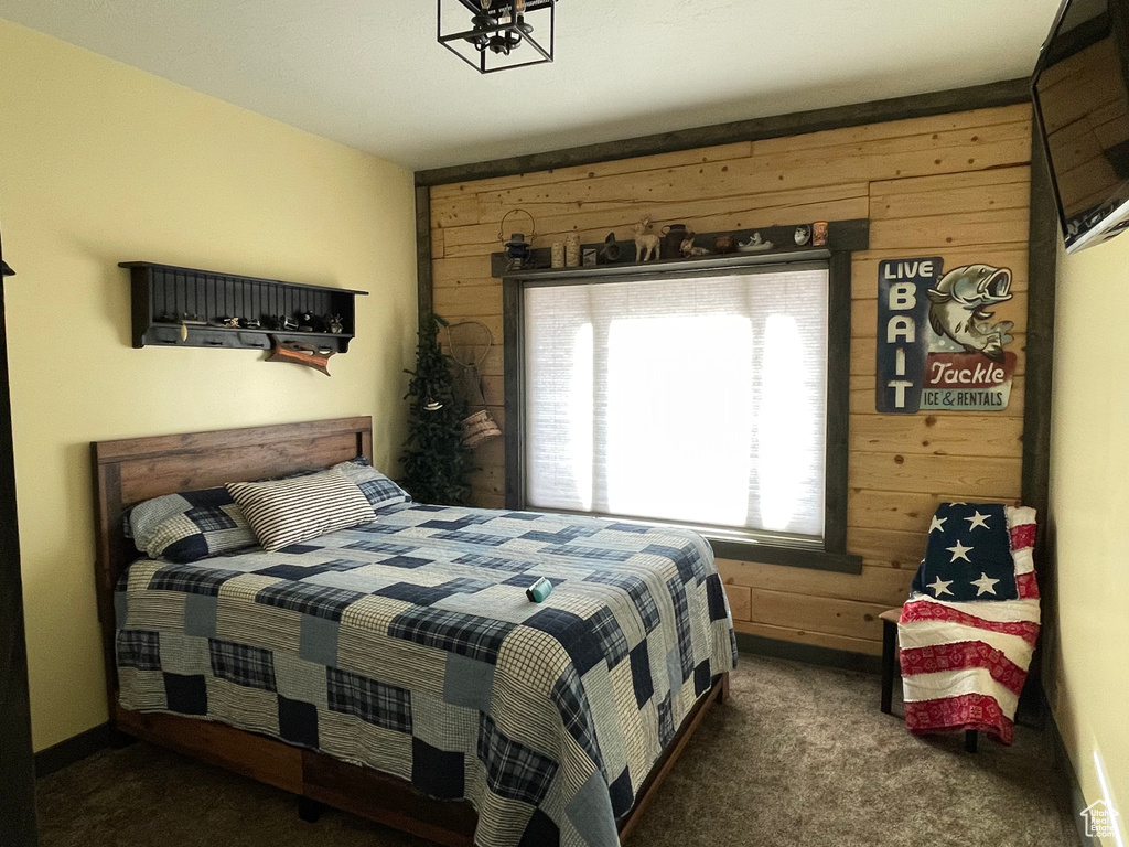 Carpeted bedroom with wood walls and a chandelier