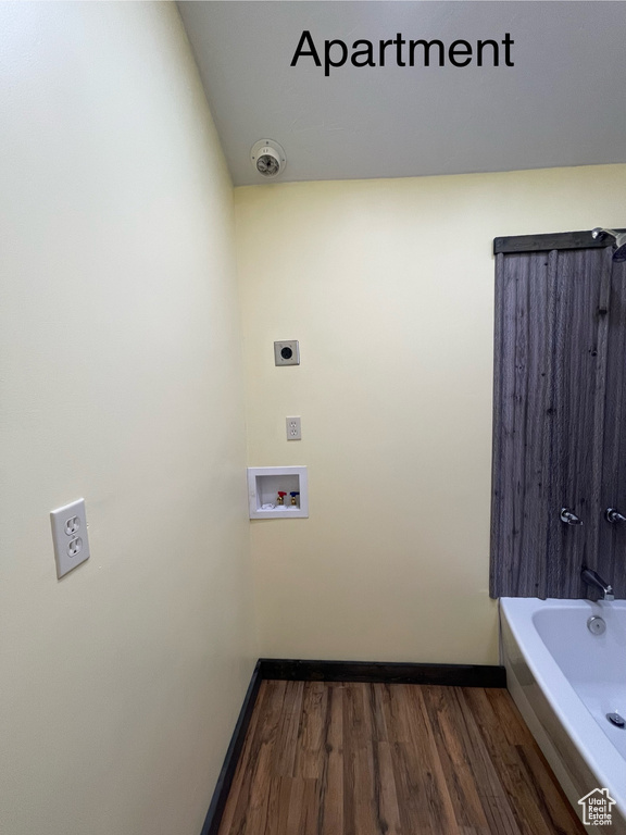 Bathroom with hardwood / wood-style floors and washtub / shower combination