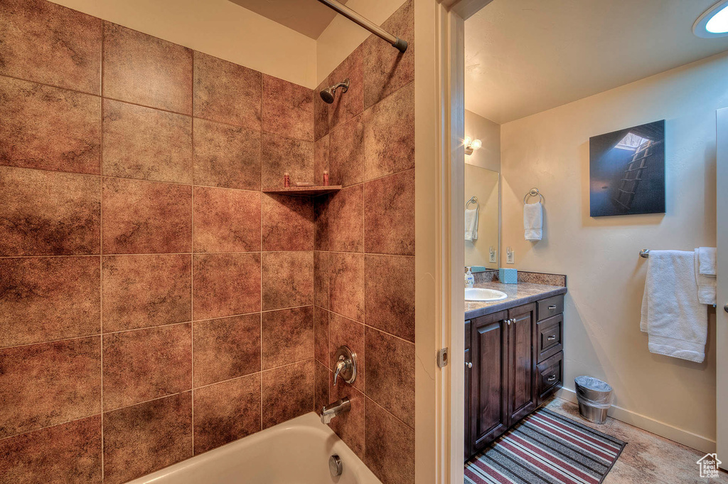 Bathroom featuring vanity, tiled shower / bath combo, and tile flooring