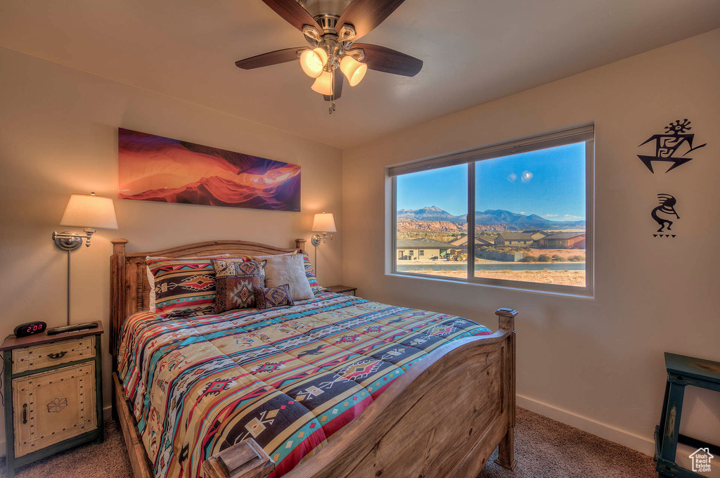 Carpeted bedroom featuring multiple windows and ceiling fan