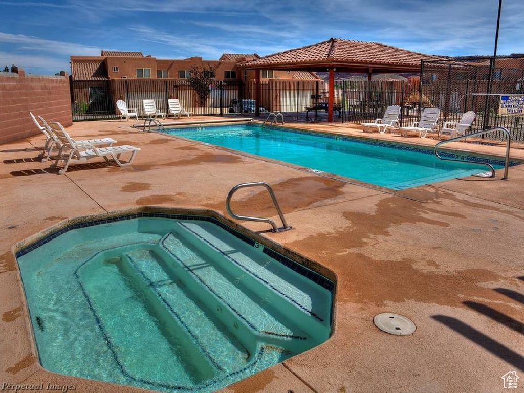 View of pool with a patio area and a hot tub