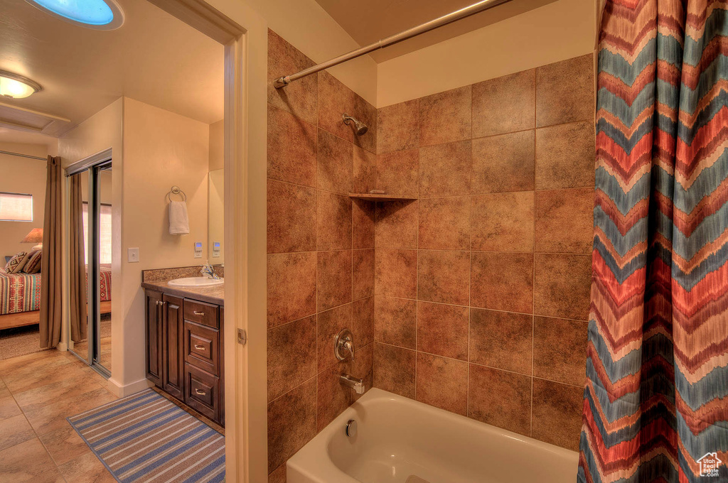 Bathroom with tile floors, shower / tub combo with curtain, and vanity