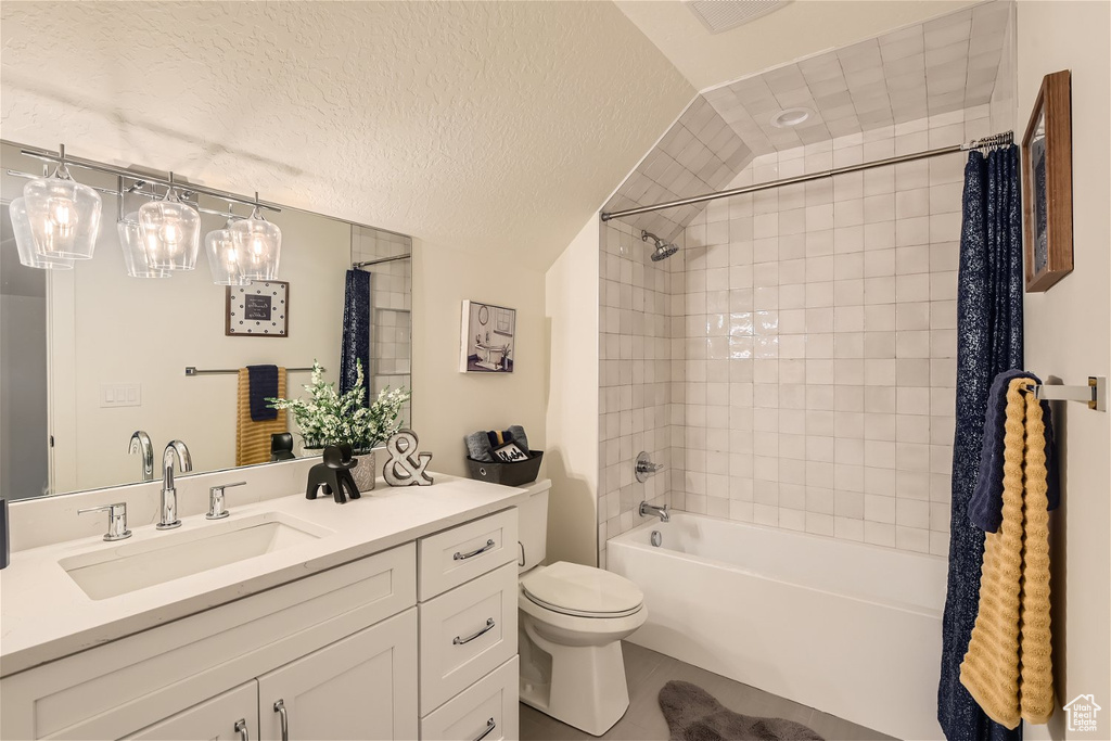 Full bathroom with toilet, vanity with extensive cabinet space, vaulted ceiling, shower / bath combo with shower curtain, and a textured ceiling