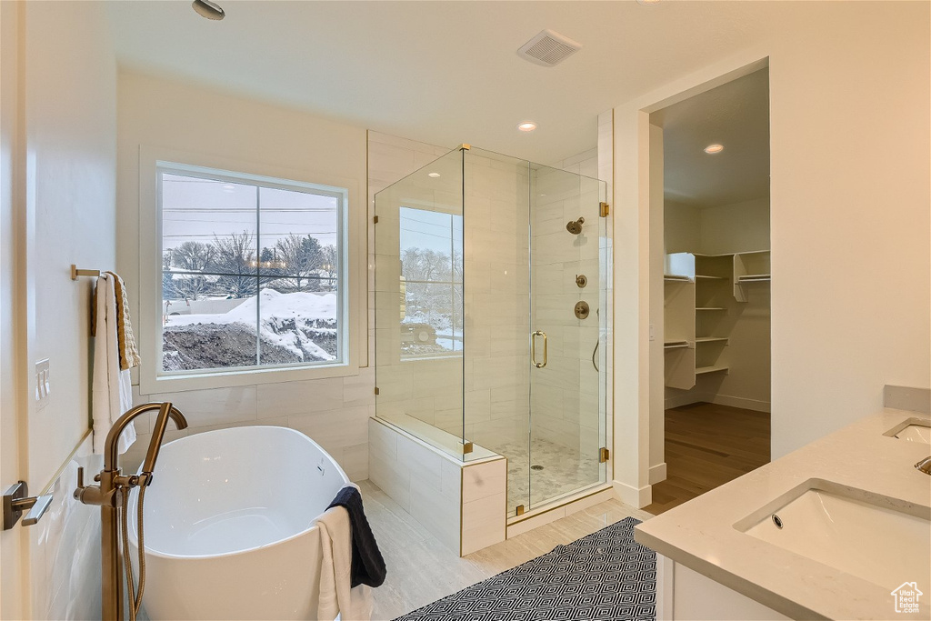 Bathroom featuring hardwood / wood-style floors, dual vanity, and plus walk in shower