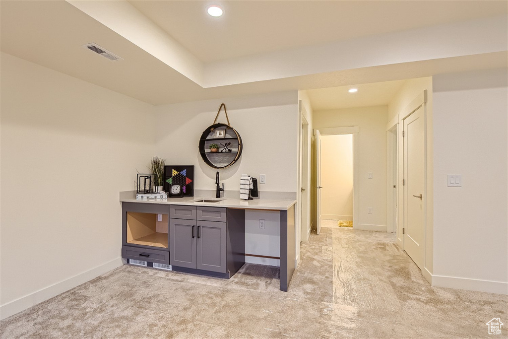 Interior space with sink, gray cabinetry, and light colored carpet