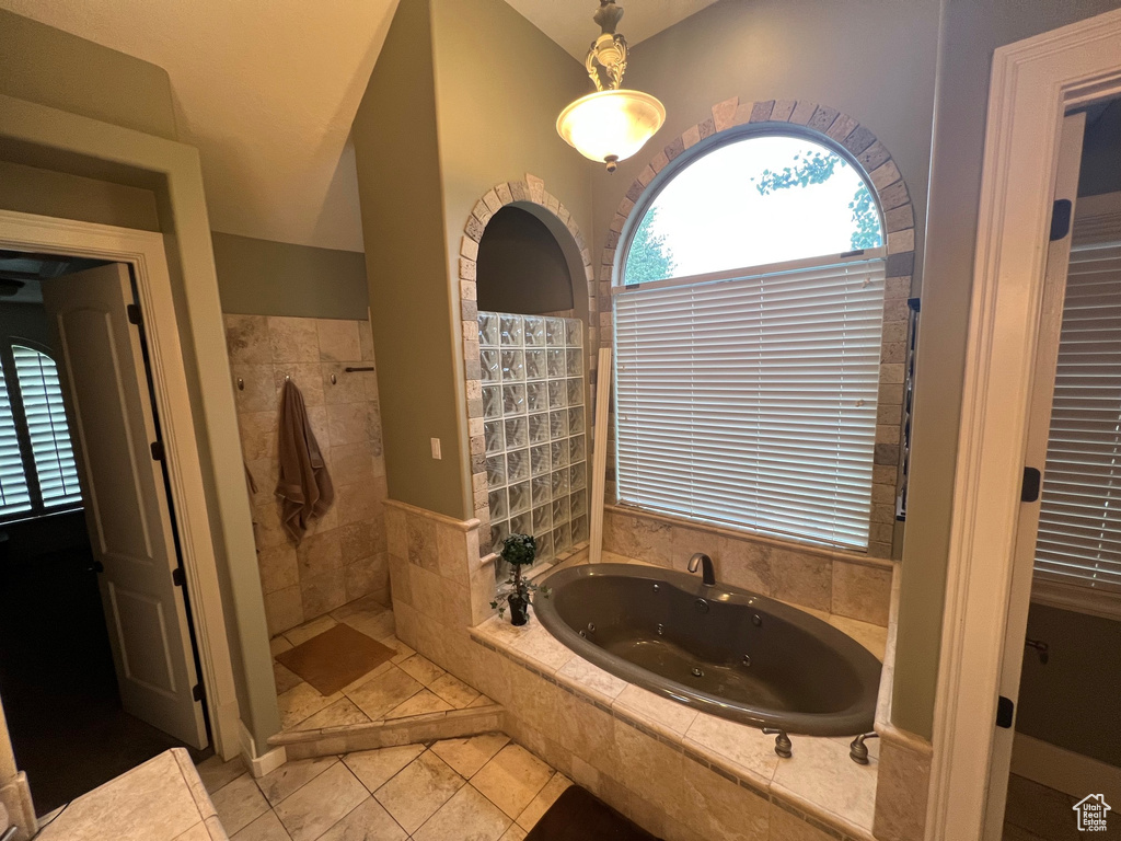 Bathroom with tile floors, tiled bath, and vaulted ceiling