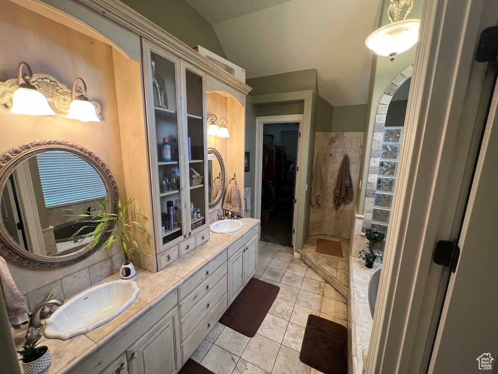 Bathroom featuring dual sinks, tile flooring, lofted ceiling, and oversized vanity