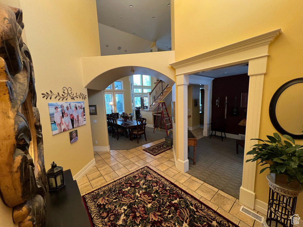 Foyer with light tile flooring, decorative columns, and high vaulted ceiling