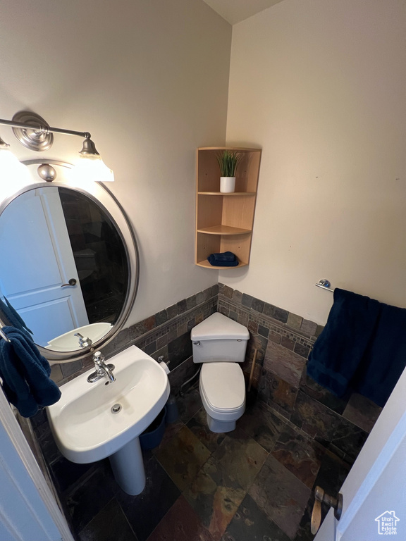 Bathroom with sink, toilet, tile walls, and tile flooring