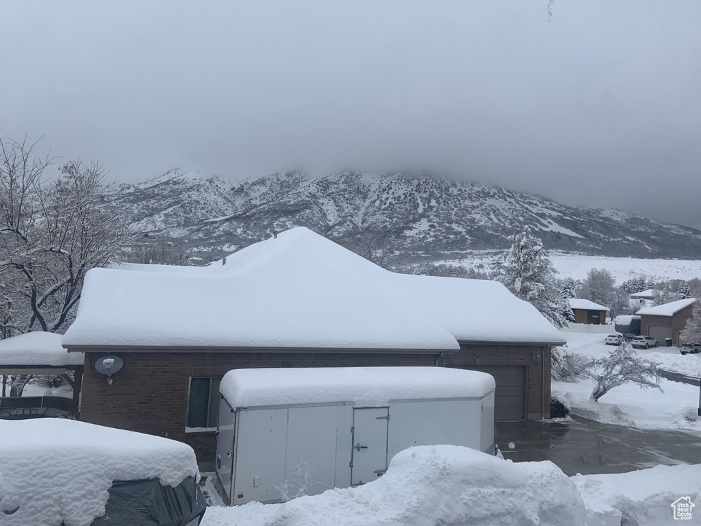 Snow covered property featuring a garage and a mountain view