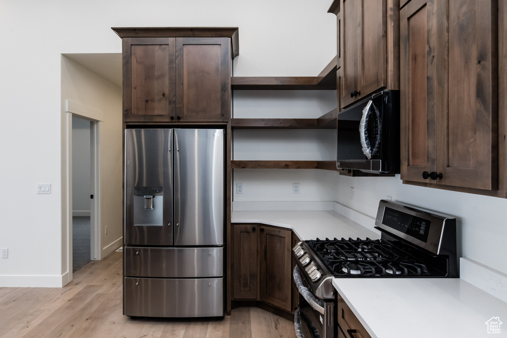 Kitchen with stainless steel appliances, light wood-type flooring, and dark brown cabinets