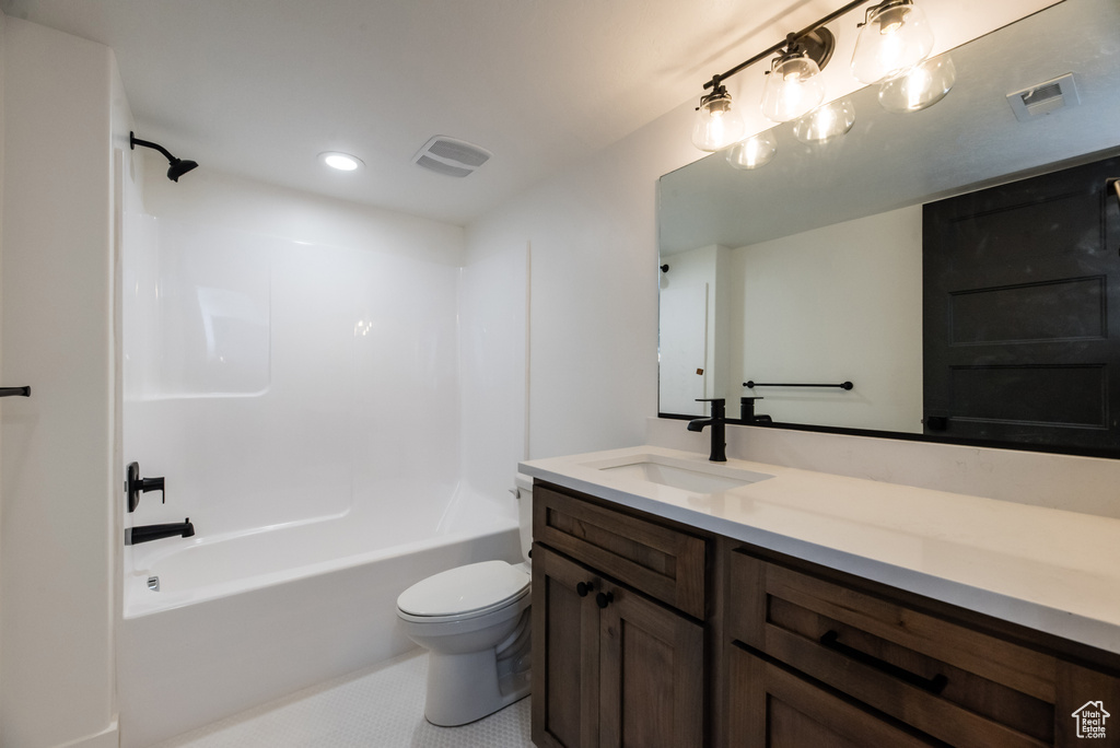 Full bathroom with  shower combination, toilet, and vanity with extensive cabinet space