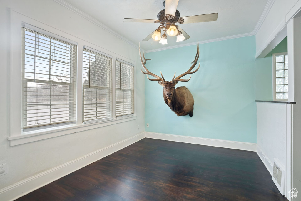 Empty room featuring ornamental molding, dark hardwood / wood-style floors, and ceiling fan