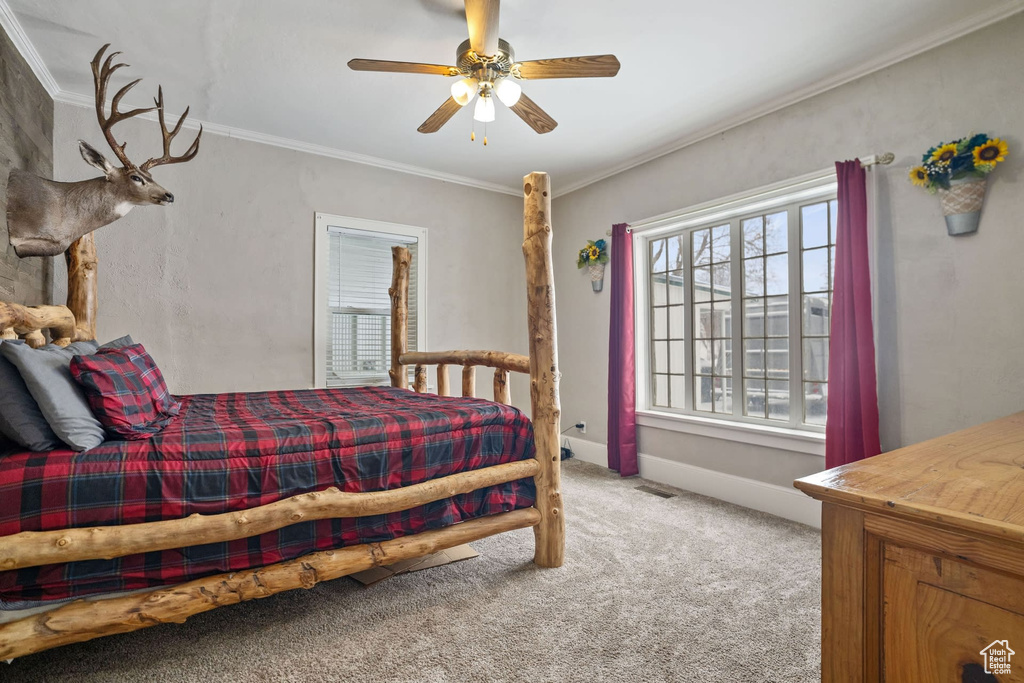 Bedroom featuring ornamental molding, light colored carpet, and ceiling fan