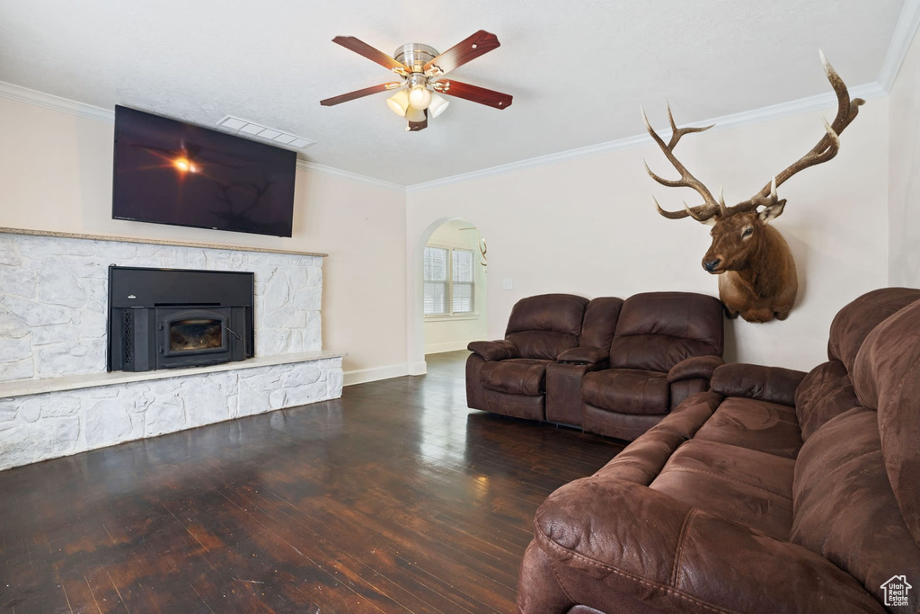 Living room featuring dark hardwood / wood-style floors, crown molding, a fireplace, and ceiling fan