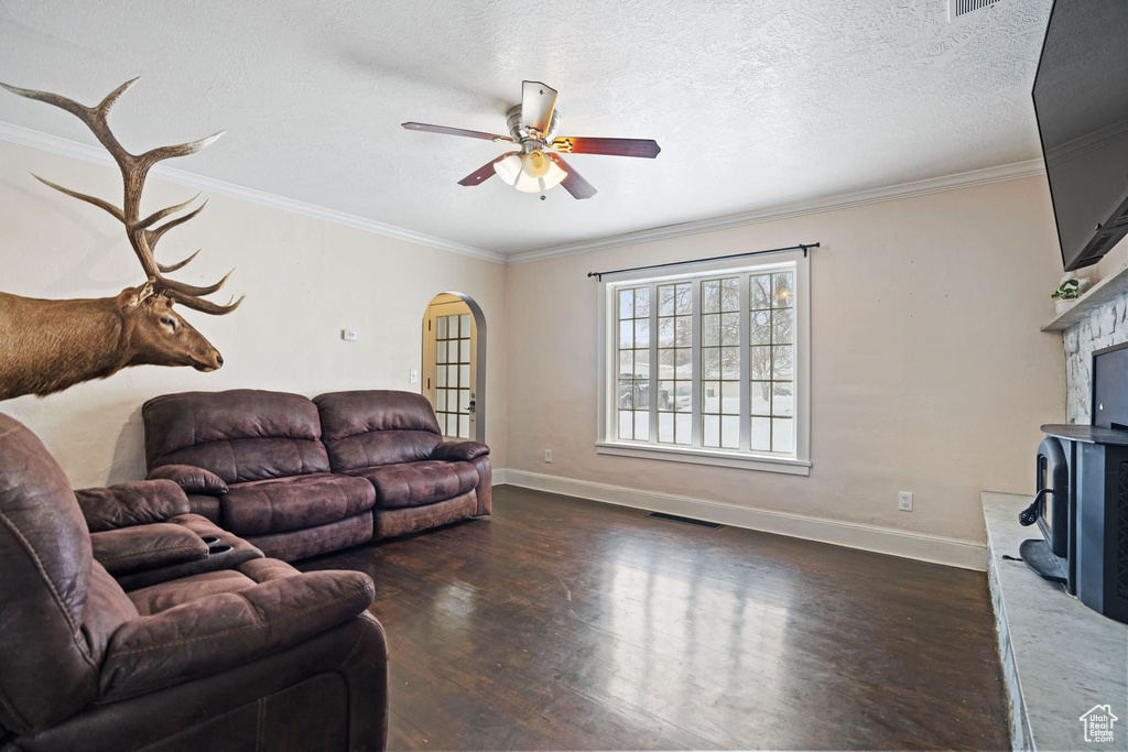 Living room featuring crown molding, a textured ceiling, dark hardwood / wood-style floors, and ceiling fan