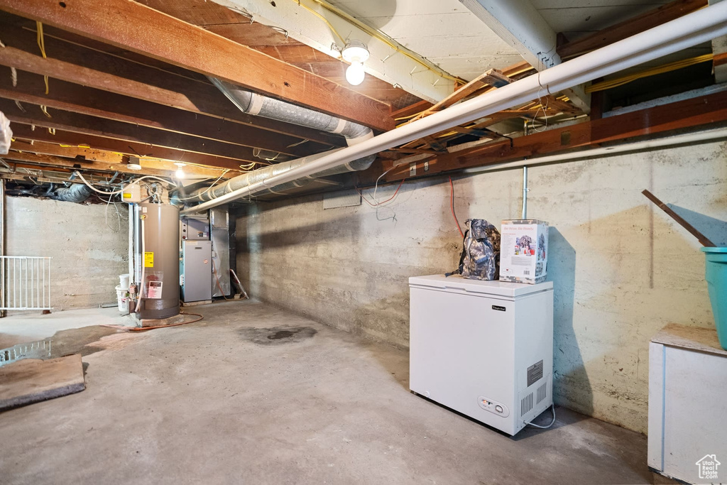 Basement with fridge, gas water heater, and heating utilities