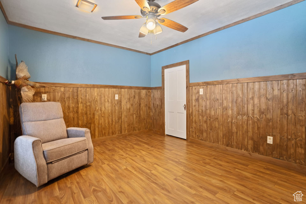 Unfurnished room featuring crown molding, wood walls, light hardwood / wood-style flooring, and ceiling fan