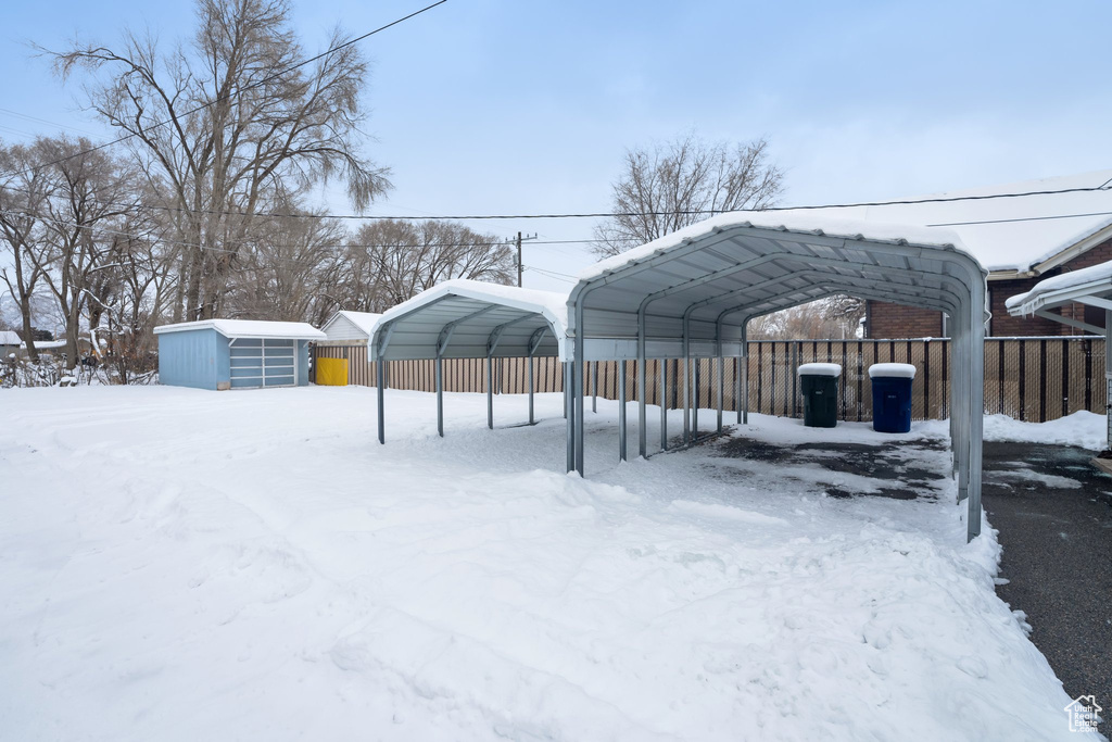 Snow covered parking featuring a carport