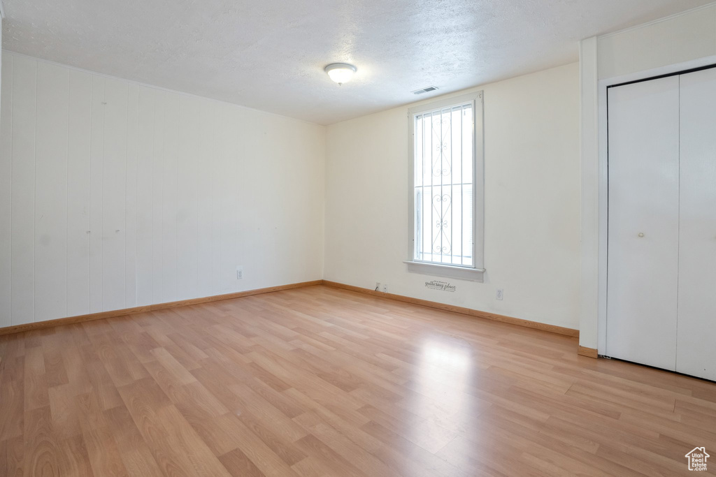 Unfurnished bedroom with light hardwood / wood-style floors, a closet, and a textured ceiling