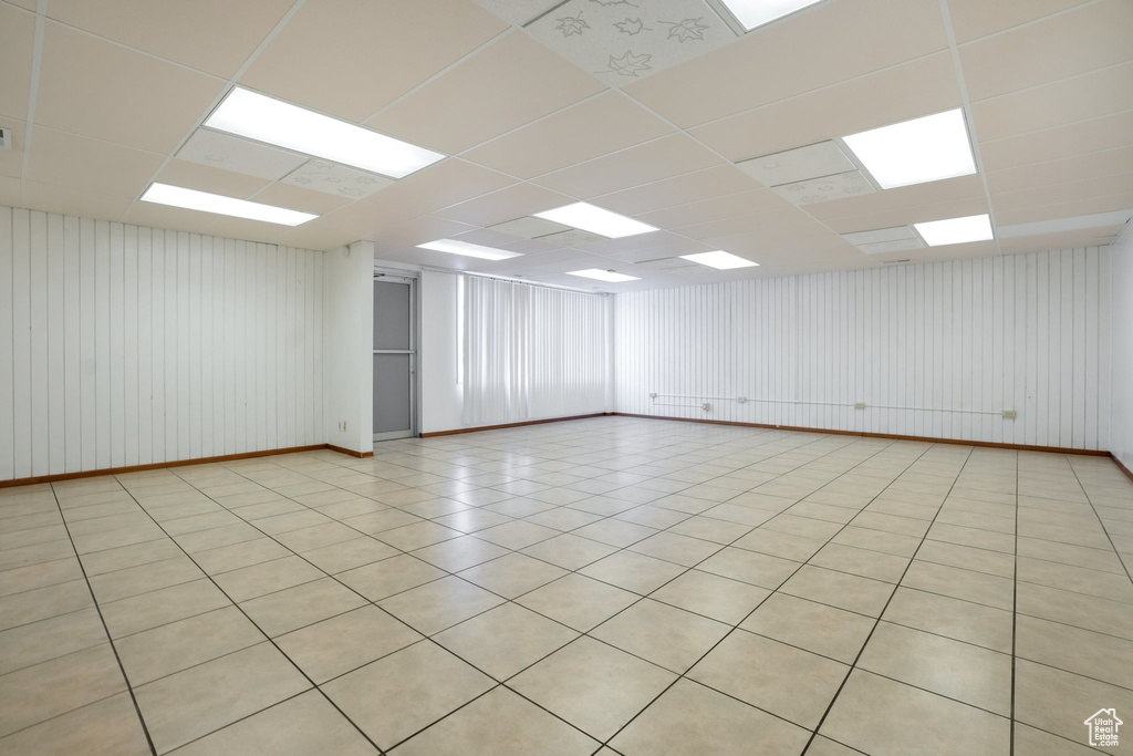 Empty room with a paneled ceiling and light tile floors